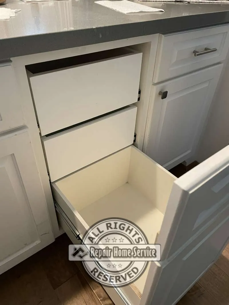 Custom cabinet drawer installation in progress with newly fabricated drawer boxes fitted inside existing white cabinetry beneath gray countertop.