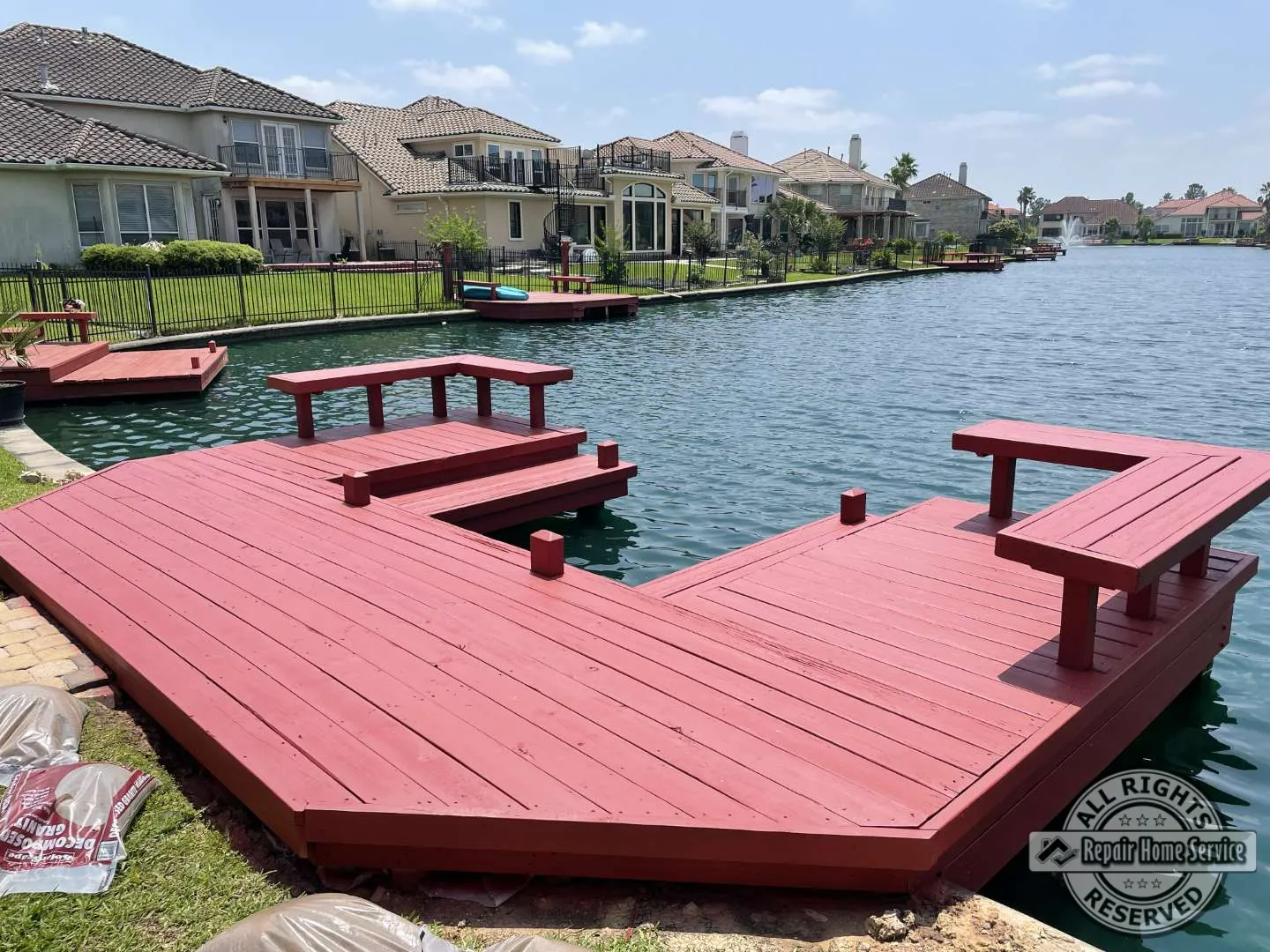 Completed red-stained waterfront deck restoration in Houston TX 77065 with multi-level platforms, benches, and lake views.