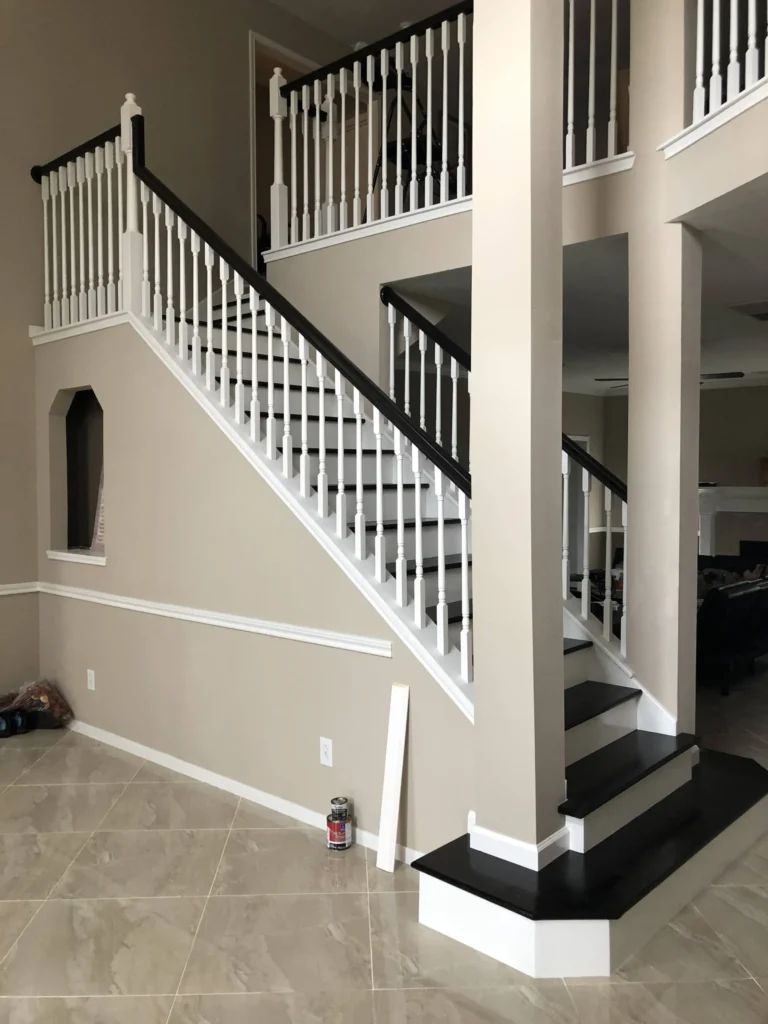 Completed two-story stair remodel in Cypress TX showing Black Coffee stained Red Oak treads, white maple risers, white balusters, and a glossy handrail in an open Houston-area entryway.