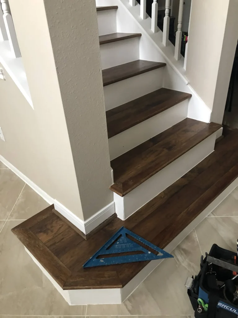 Close-up of Black Coffee stained Red Oak treads and white maple risers wrapping a column at the base of a staircase remodel in Cypress TX, with a speed square on the bottom step