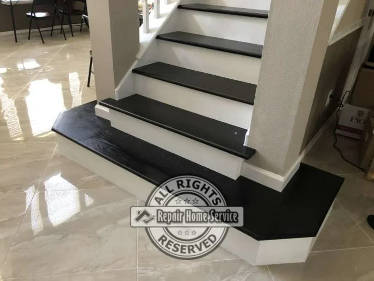 Low-angle view of completed dark stained Red Oak treads and white risers on a custom starter landing above polished tile flooring in a Cypress TX stair remodel.