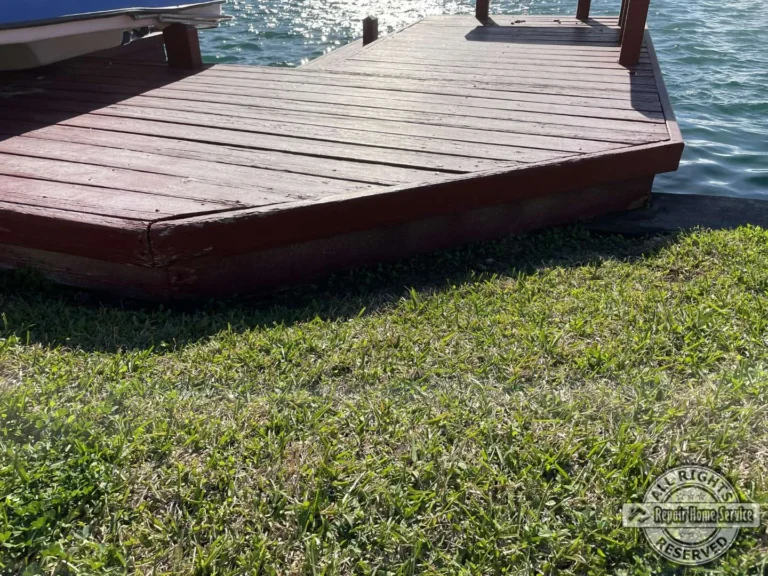 Restored multi-level lakeside deck in Houston TX with deep red stain, built-in benches, and decorative post caps along the water.