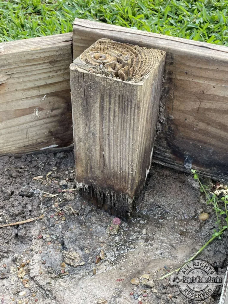 Close-up of rotted wooden deck support post at wet ground level in Houston TX before structural replacement.