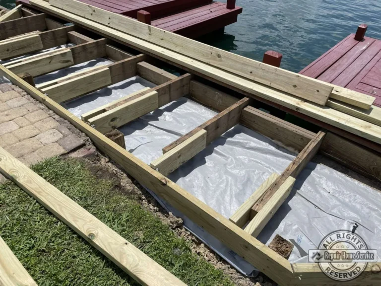 Deck framing repair in progress in Houston TX with new pressure-treated joists, landscape fabric, and lakefront stone paver edge.