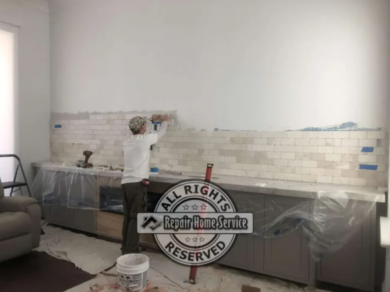 Living room wall during natural stone backsplash installation behind custom entertainment cabinets and built-in shelving