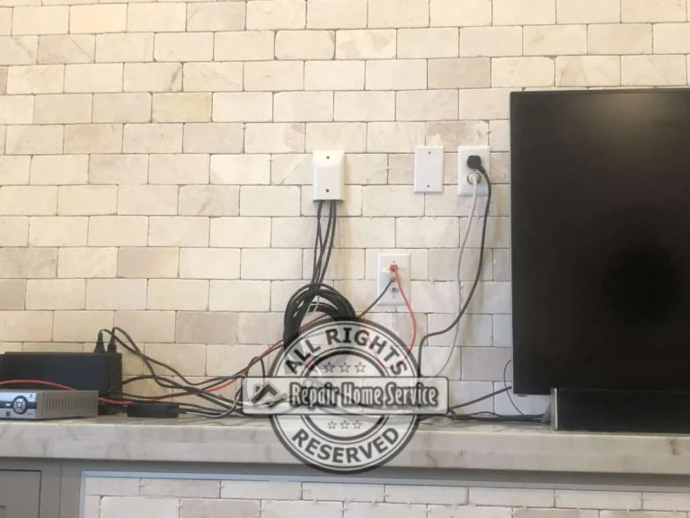 Natural stone backsplash detail behind TV area with outlets and wiring above granite countertop for entertainment wall