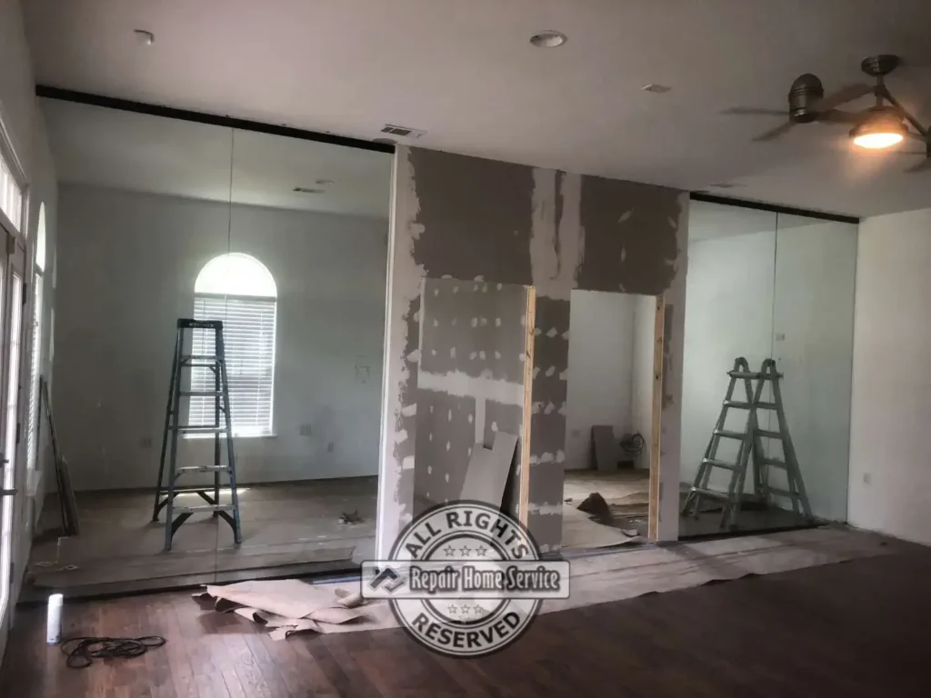 Drywall finishing and large glass wall installation in progress for private office areas within a professional commercial workspace renovation.
