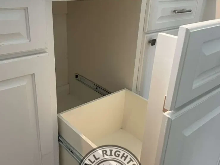 Existing kitchen-style cabinet with pull-out storage drawer removed during custom cabinet modification project to create space for a compact freezer in Spring TX.