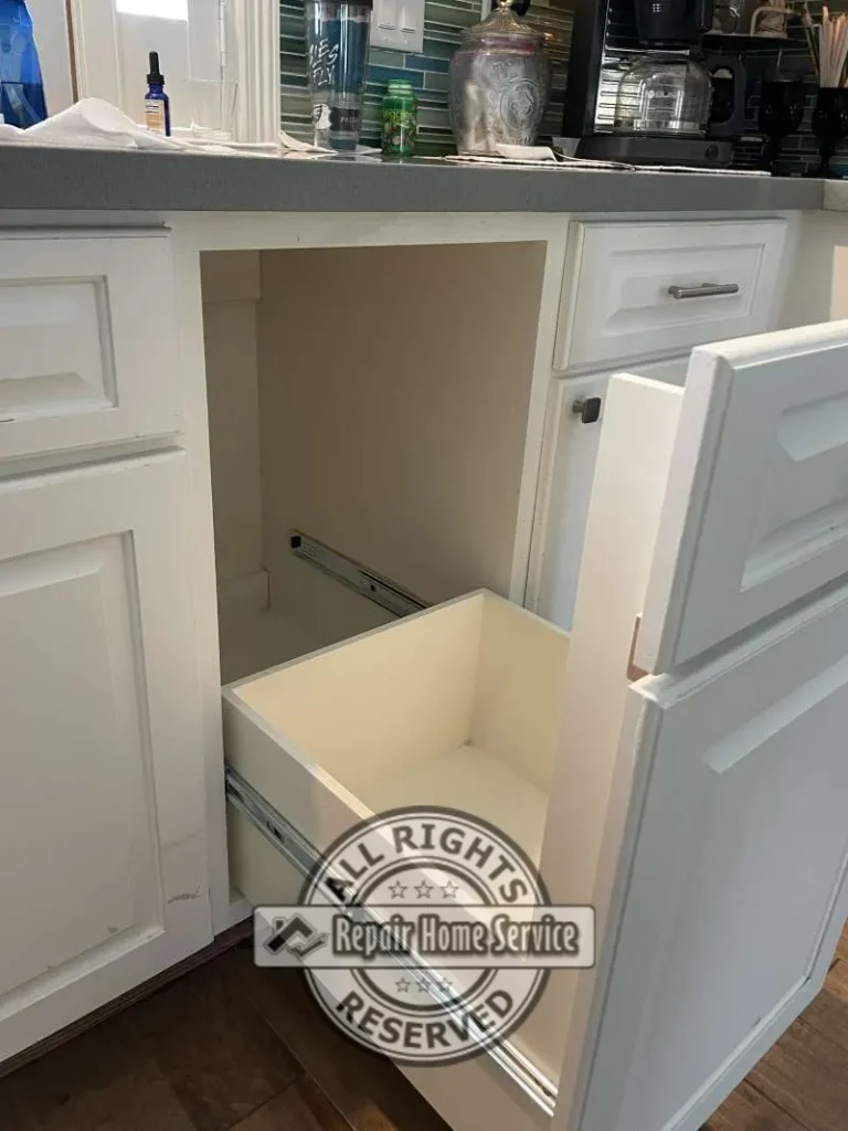 Existing kitchen-style cabinet with pull-out storage drawer removed during custom cabinet modification project to create space for a compact freezer in Spring TX.