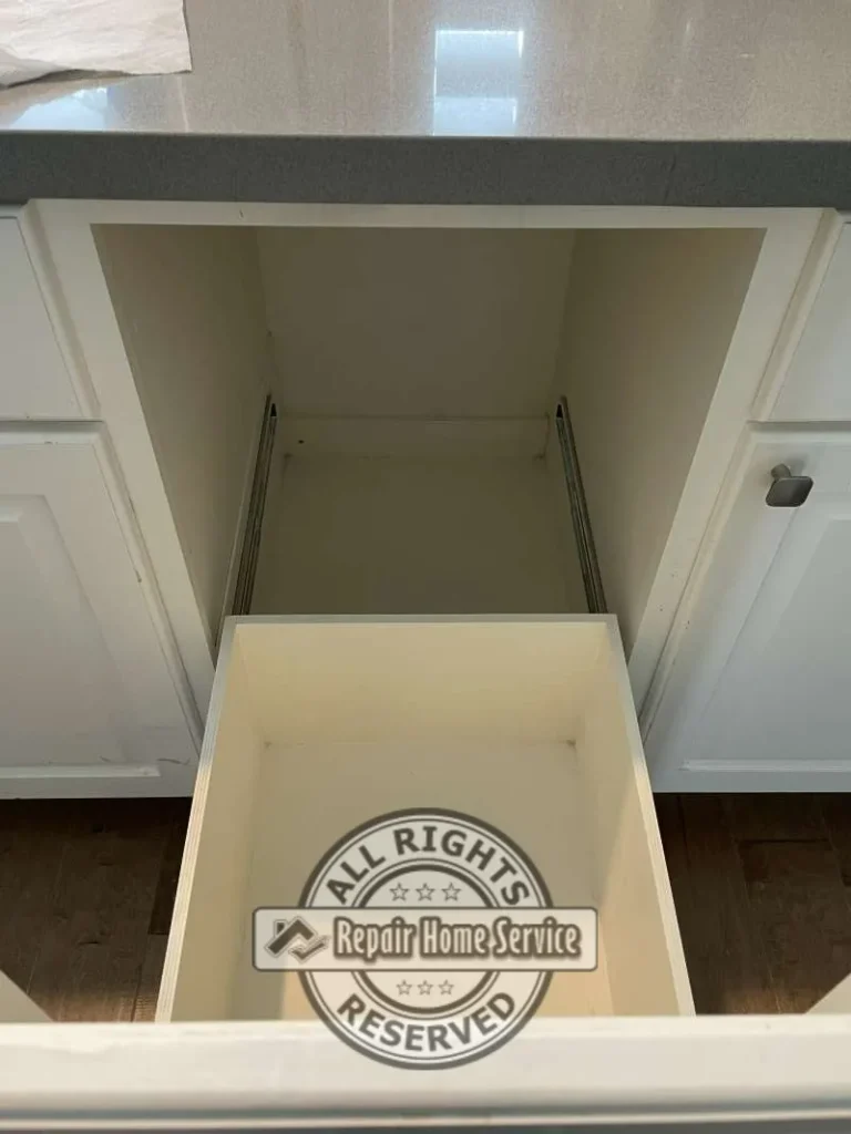 Interior view of modified base cabinet opening showing drawer slide hardware and custom storage compartment before installation of new drawer boxes.