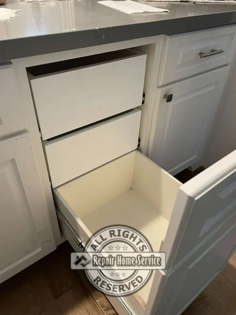 Custom cabinet drawer installation in progress with newly fabricated drawer boxes fitted inside existing white cabinetry beneath gray countertop.