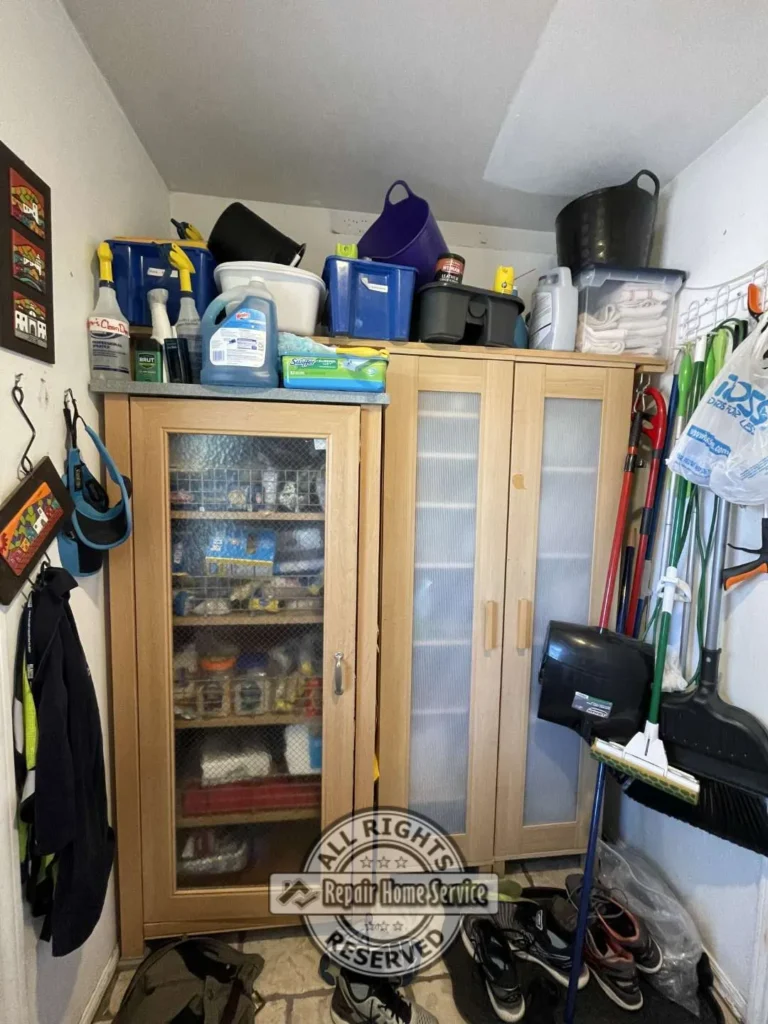 Existing laundry room storage area with freestanding cabinet and household supplies before custom built-in cabinet installation in Houston TX.