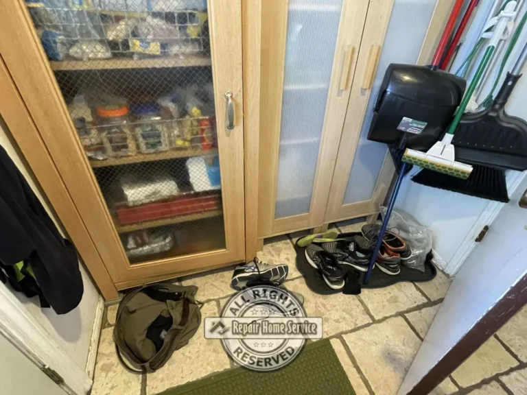 Close-up view of original storage cabinet and cluttered laundry room organization before remodeling project.
