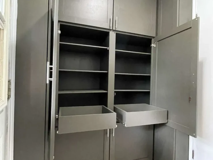Original laundry room before renovation showing limited wall cabinets and exposed storage above washer and dryer.