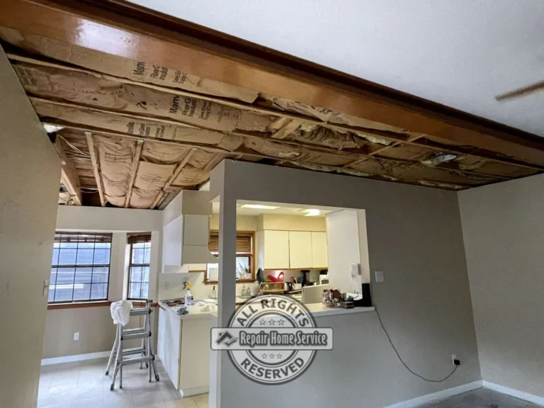 Water-damaged ceiling removed in open living room with exposed insulation and wood trim during Houston TX ceiling repair project.