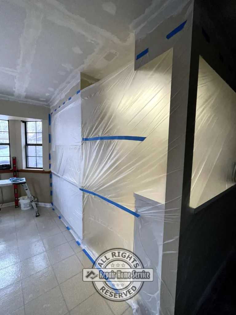 Interior containment setup with plastic sheeting protecting kitchen surfaces during ceiling restoration and drywall repair in Houston TX