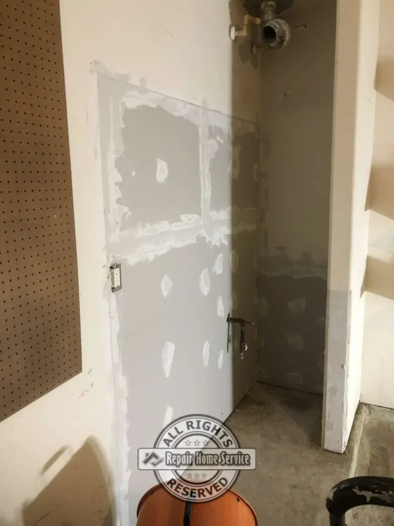 Utility closet drywall repair in progress with new Sheetrock panels, taped seams, joint compound patches, pegboard wall, and water heater opening.