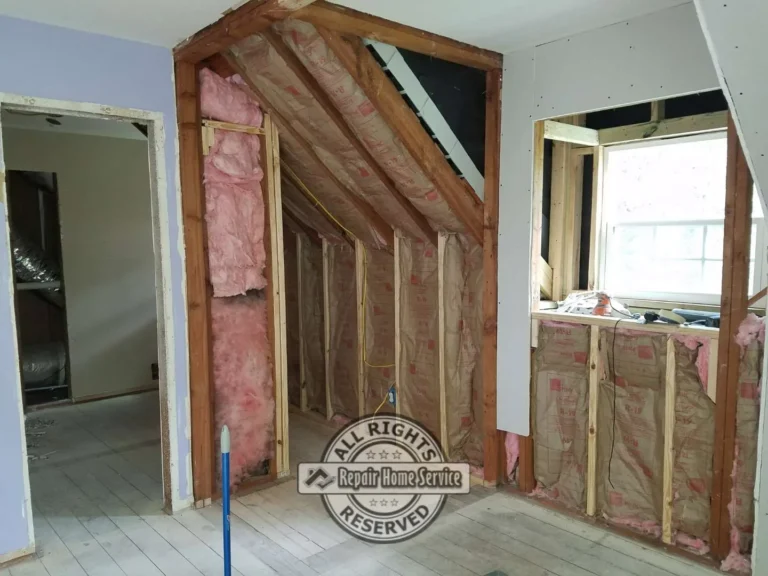 Interior remodel before drywall installation showing exposed wall framing, pink insulation, window opening, doorways, and unfinished attic-style wall sections.