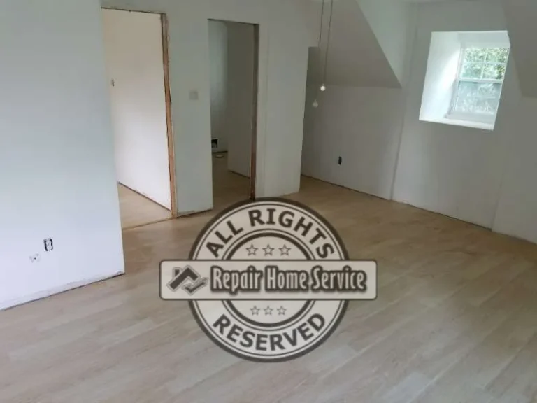 Upstairs room after drywall installation with smooth painted walls, sloped ceiling, window trim, doorway openings, and light wood flooring.