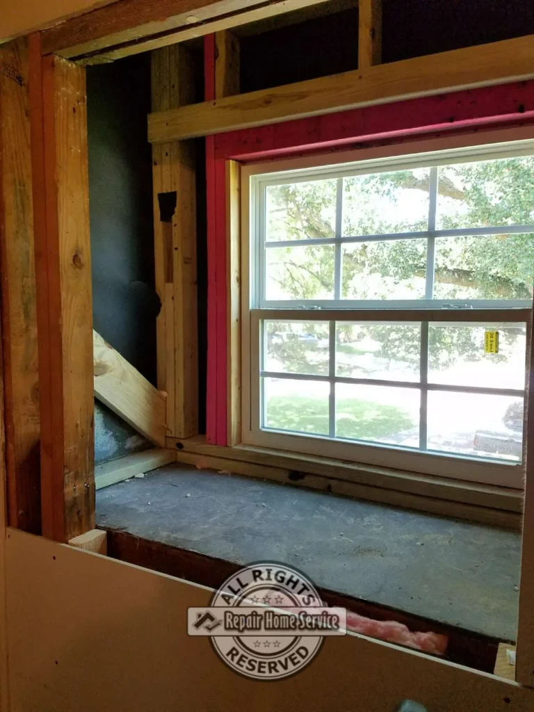 Window opening during remodel with exposed framing, insulation, rough sill, and new window set into an unfinished drywall wall.