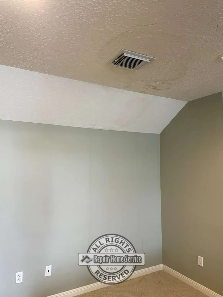 Bedroom ceiling before drywall repair showing textured ceiling, HVAC vent, wall trim, carpet, and visible water staining near the ceiling corner.
