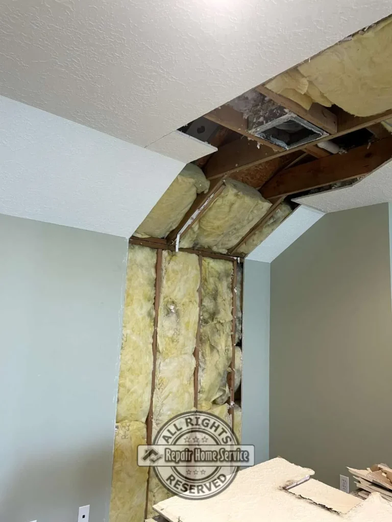 Bedroom wall and sloped ceiling opened for Sheetrock repair with exposed framing, insulation, ductwork, and removed damaged drywall in Houston TX.